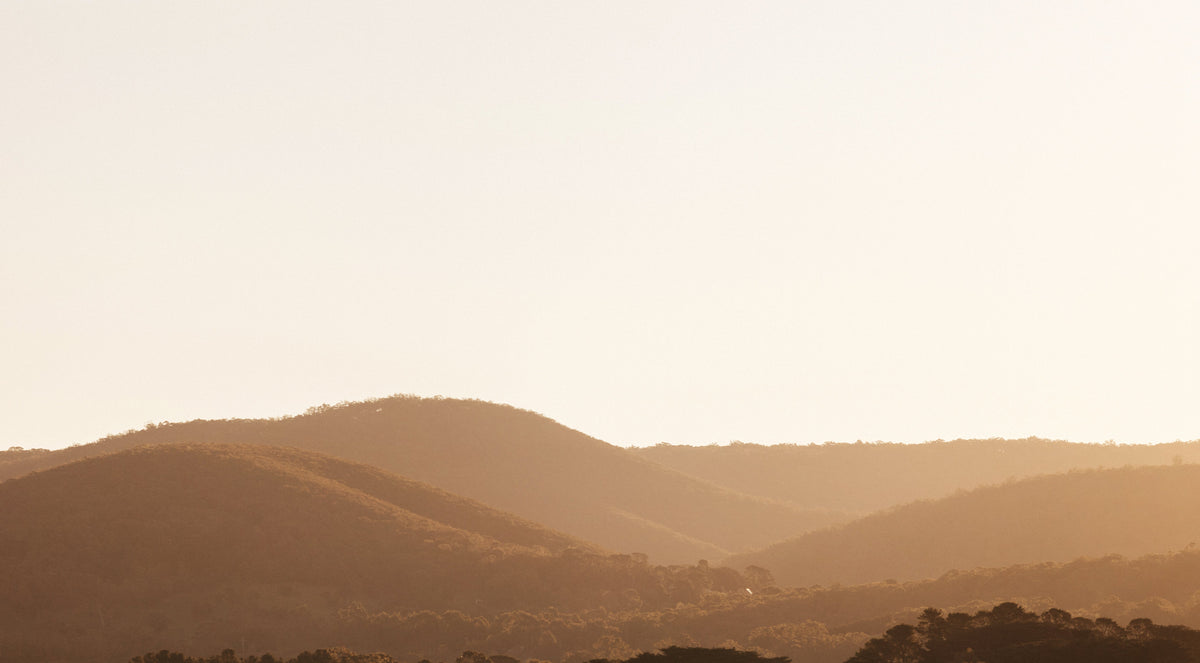 Sunset over the Macedon Ranges near Deep Creek, showing natural volcanic hills and native forest.