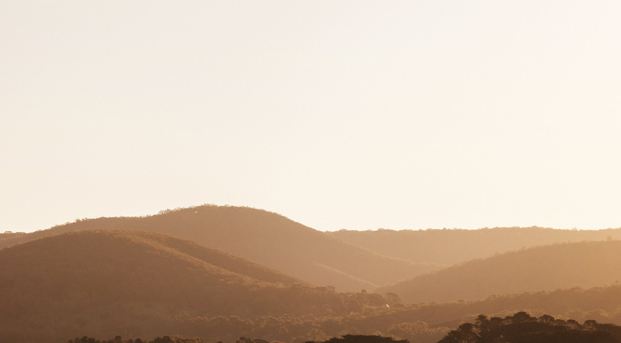 Sunset over the Macedon Ranges near Deep Creek, showing natural volcanic hills and native forest.